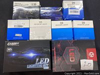 Overview of nine boxed car lighting kits arranged on a blue surface including LED lighting kits and various 3D shadow light kits