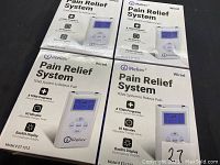 Four boxed iReliev Pain Relief System TENS units showing front packaging with device image and product features