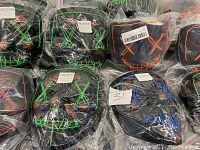 Multiple LED wire Halloween masks in sealed plastic bags showing green, blue and orange wiring designs on black masks.