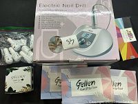 Electric nail drill with its packaging box, multiple gel polish boxes and a small bag with white nail drill bits