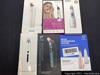 All six blackhead remover devices in their original boxes arranged flat on a black background.