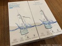 Two boxed AIWO branded wireless oral irrigator tooth cleaning tools, shown front view design with key features printed on the box including reservoir capacity, 360-degree nozzle rotator, waterproof and rechargeable battery.