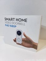 Box front view showing product name 'Smart Home Video Doorbell FHD 1080P' with an image of the doorbell held in a person's hand.
