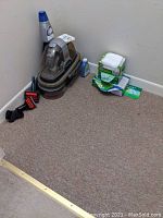 Bissell Spot Carpet Cleaner with cleaning solution bottle, multiple attachments, and boxes of Swiffer dust cloths on carpeted floor showing wear