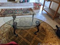 Full view of the oval glass-top coffee table on patterned rugs.