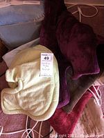 Three heating pads in burgundy, brown, and cream colors piled together showing cords and controllers