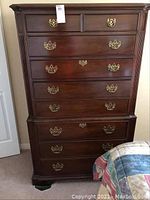 Full front view of the tall boy dresser showing all eight drawers and brass handles.