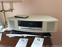 Front view of Bose Wave Music System showing digital display, speaker grilles, and remote on top