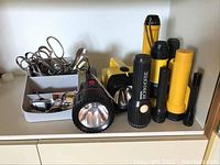 Group of assorted flashlights and scissors in metal organizer on flat surface