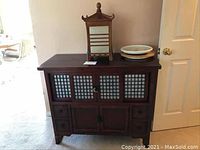 Front view of the Asian style wooden cabinet with lattice sliding doors and drawers, showing top surface with pagoda light and plates.