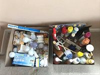 Box of assorted cleaning supplies and tools including brushes, spray bottles, and various liquid cleaning products