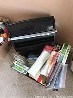 FoodSaver vacuum sealing machine on top of box containing various vacuum sealer bags and rolls.