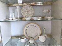 Multiple Lenox china items displayed on glass shelving including platter, vase, salt and pepper shakers, candy dish, sugar and creamer, and other small dishes.