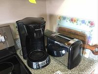 Black & Decker coffee maker and toaster shown on kitchen counter with cutting boards behind