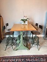 Two industrial adjustable stools with dark wood seats and backrests on green metal frames