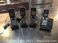 Photo of Panasonic digital wireless phone set components arranged on table including base station, three handsets, power cables and cords.