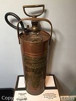 Front side view showing the extinguisher's handle, hose, and upper mechanism.