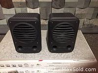 Front view of a pair of Tannoy CPA5 compact studio speakers on a flat surface, showing front grilles and dual ports.
