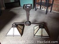 Chandelier with two square pyramid slag glass shades and heavy metal frame, shown unlit in a dimly lit room.
