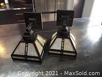 Pair of Arts & Crafts style wall sconces placed on a kitchen counter showing trapezoidal slag glass panels with dark metal framing
