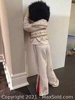 Rear view of doll showing white jumpsuit with multicolored embroidery and black hair.