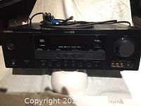 Front view of Yamaha HTR-6140 AV receiver showing control panel, buttons, dial, and front inputs