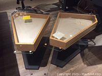 Pair of trapezoidal end tables showing glass tops, maple framing and black bases