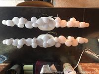 Top view of two long white bathroom sconces showing linked rounded bulb shapes.