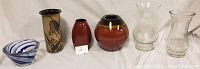 All five vases and one glass bowl arranged in a row showing different shapes, colors, and designs.