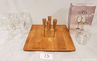 Photo showing wooden cheese board with four magnetic cutting tools fitted in the center, six wine glasses, and unopened Lovia wine carafe box