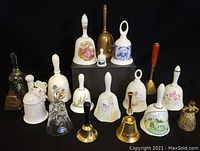 Eighteen assorted bells of various materials and designs arranged on black background, includes porcelain, brass, crystal bells of different sizes and decorations