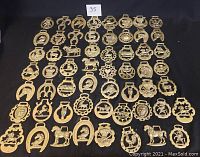 Overview of 57 brass buckles and medallions arranged on a black background