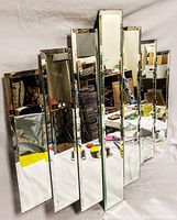 Front view showing full abstract design mirror made up of seven staggered vertical mirrored panels.