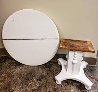 Front view of the round white painted table top detached and the white painted pedestal base with natural wood top surface.
