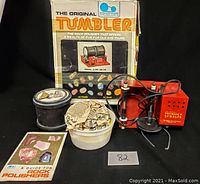 Thumler's Original Tumbler rock polisher with power unit, rough rocks in container, guide booklet, and original box
