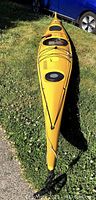 Full-length view of yellow kayak on grass showing deck rigging and hatches