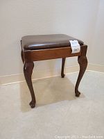 Side view of rectangular wooden sewing stool with dark brown pleather padded seat lid on.