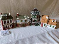 Wide shot showing all five Department 56 Dickens' Village collectible ceramic buildings arranged in a row against a neutral background. Original boxes are visible.