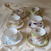 Photo showing the 6 teacups on matching saucers with various floral and gold designs from a top angle.