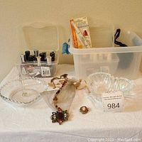 Wide view of two clear crystal heart-shaped bowls, a large Chico's necklace, small floral cameo brooch, and a nail polish kit with multiple bottles in a plastic container.