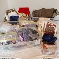 Wide view of multiple storage bins with assorted pre-cut quilt pieces and quilting fabrics, with visible fabric colors including reds, blues, browns, and pattern prints.
