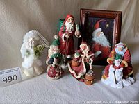 Photo showing five varied Father Christmas figurines and one framed Santa picture against a neutral cloth background.