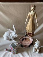 Group photo of all items: ceramic bunny, wooden lady statue, cherub figurine, watering can, and heart-shaped plate with cherub artwork