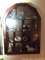 Curio cabinet with multiple compartments filled with various miniature collectibles.