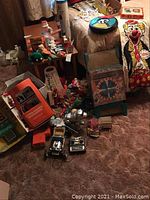 Wide view of assortment of vintage toys including remote control cars, stuffed animals, and electric pinball machine.