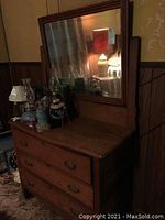 Front view of oak dresser with attached large mirror. Top surface has various decorative items. Shows mirror's cloudiness and dresser's overall condition.