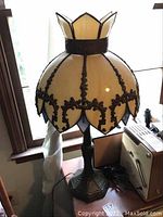 Full view of vintage stained glass table lamp showing overall shape, metal base, and stained glass shade with decorative metal trim.