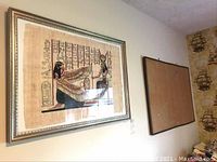 Framed Egyptian papyrus artwork on wall next to a burlap bulletin board, both hanging adjacent.