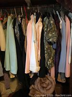 Closet view showing various vintage ladies dresses and coats in multiple colors and fabrics hanging on hangers
