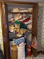 Closet with stacked vintage quilts, towels, and laundry hamper with some miscellaneous items